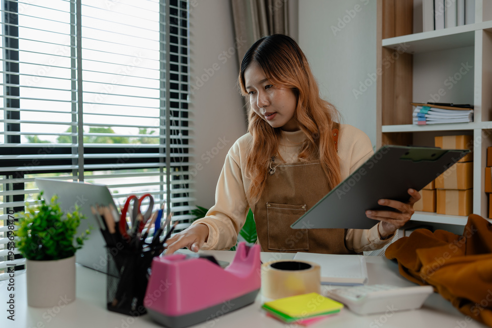 an entrepreneur or a business owner works in her office full of packages, it is a small business that she created with careful preparation, start up business of clothes an entrepreneur or a business owner works in her office full of packages, it is a small business that she created with careful preparation, start up business of clothes