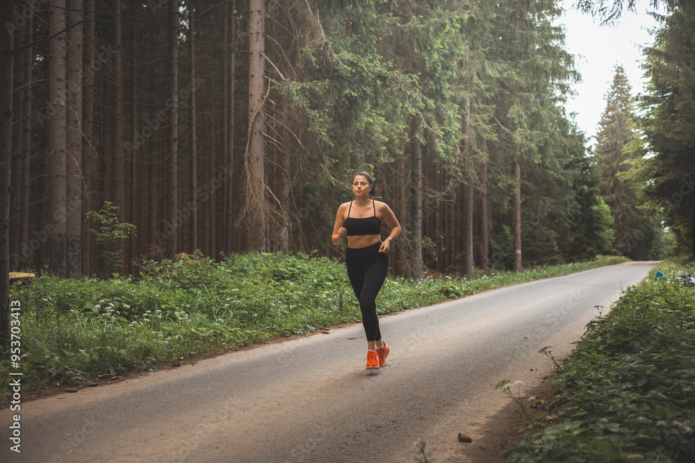 Brunette aged 20-25 in black sportswear running in nature in the evening sun. Active lifestyle. Outdoor sport Brunette aged 20-25 in black sportswear running in nature in the evening sun. Active lifestyle. Outdoor sport