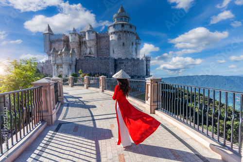 Vietnamese girl in a red ao yai dress is traveling at French village on Bana Hills in Danang, Vietnam.