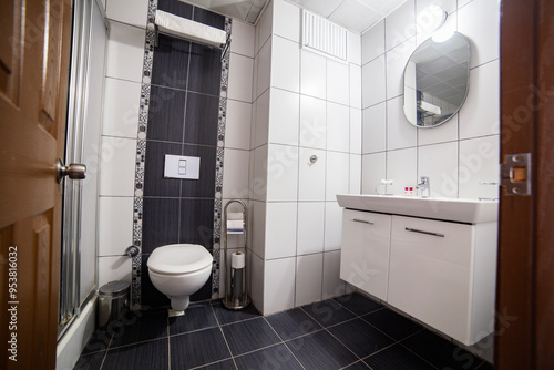 interior of a modern bathroom with toilet bowl, tiled walls and mirror 