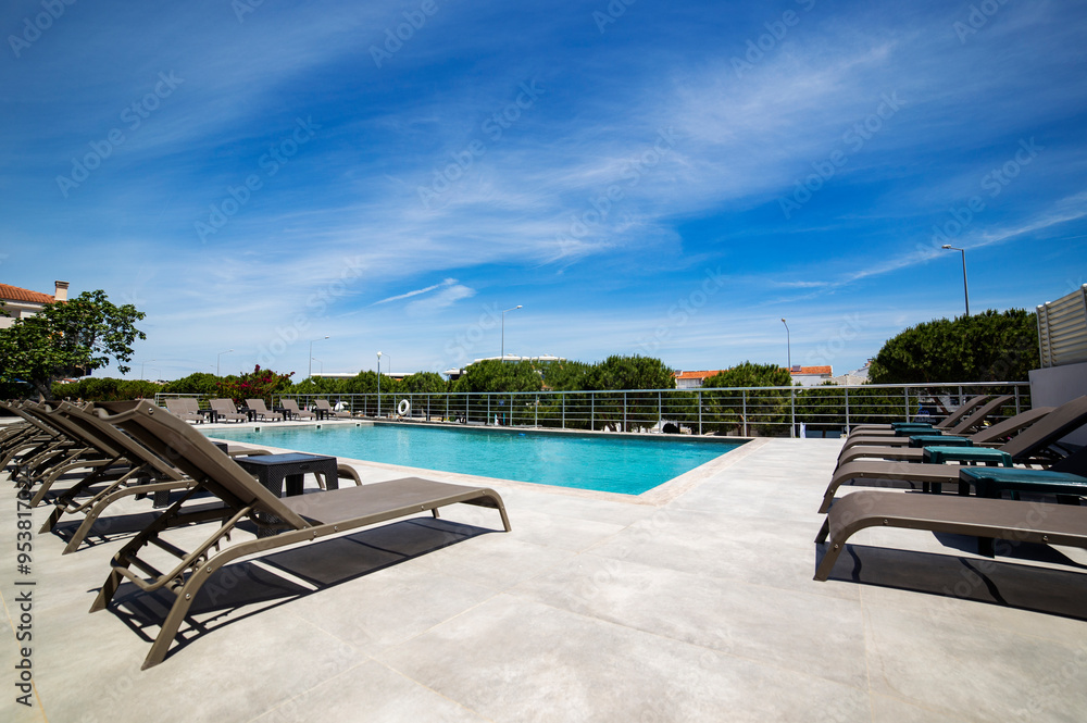 Fototapeta premium Modern poolside retreat with sun loungers in a serene urban setting