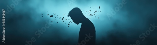 Silhouette of a person with fragments dissolving from their head against a moody blue background, symbolizing stress, anxiety, or mental breakdown. photo