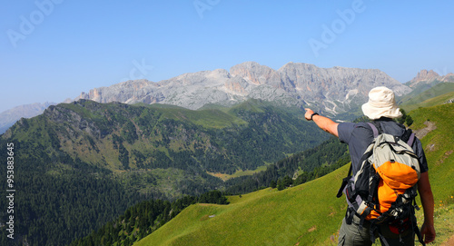 Obraz na plátne hiker with backpack on shoulders pointing to mountains out on the horizon in Ita