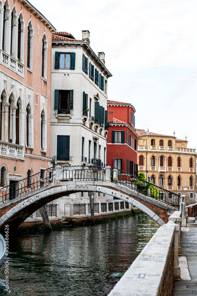 Naklejka premium A charming canal with colorful buildings and a stone bridge in a quiet Venetian neighborhood during the late afternoon