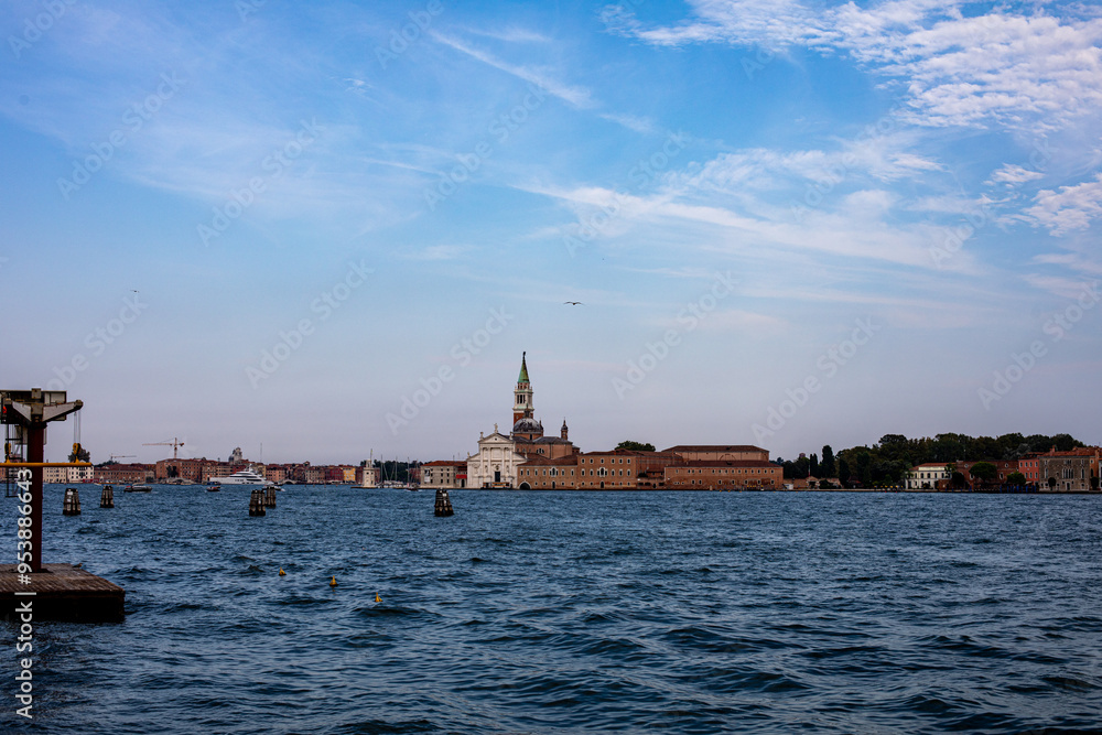 A serene view of the Venetian skyline featuring historic buildings and waterway activities under a clear blue sky A serene view of the Venetian skyline featuring historic buildings and waterway activities under a clear blue sky