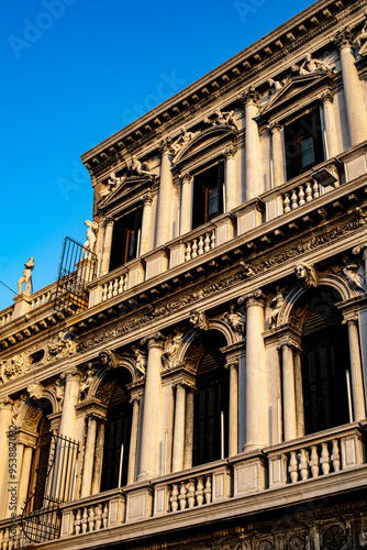 Historic architectural details of a grand building in Venice, showcasing ornate columns and decorative elements under a clear blue sky