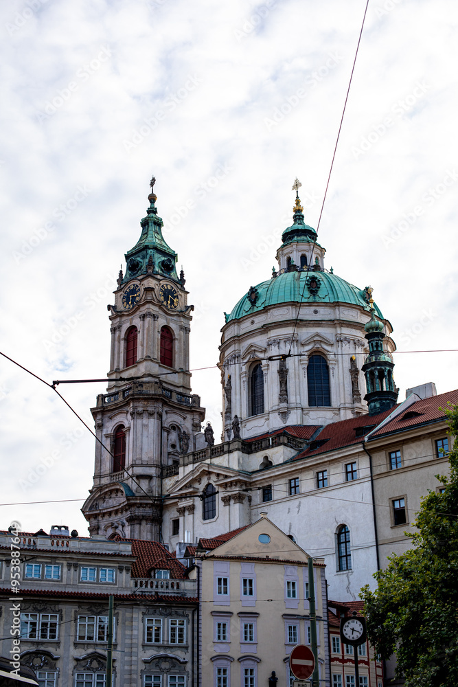 Fototapeta premium St. Nicholas Church in Prague showcasing its impressive Baroque architecture under a cloudy sky during the afternoon