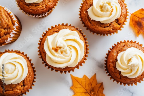 pumpkin muffins with a generous swirl of maple cream cheese frosting on top, some muffins cut open to show the creamy filling