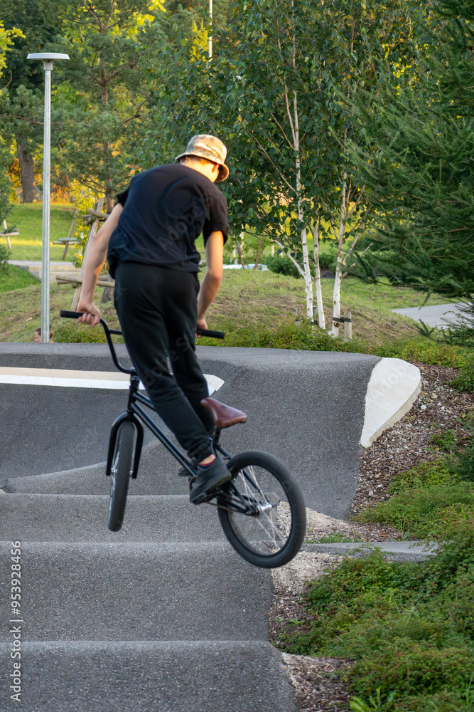 Fototapeta premium Young man doing tricks on a BMX bike. BMX freestyle against the backdrop of urban landscape. Extreme sports is very popular among youth.