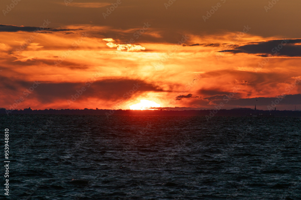Fototapeta premium The sky is on fire in this photo of the sun setting over the bay in New Jersey. Image captured from Fort Hancock at Sandy Hook on August 21, 2024.