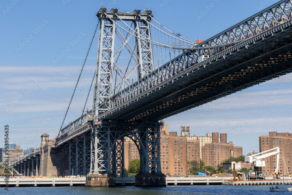 A clear day view of the Manhattan skyline and Williamsburg Bridge with modern skyscrapers under a blue sky A clear day view of the Manhattan skyline and Williamsburg Bridge with modern skyscrapers under a blue sky