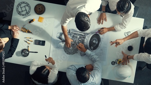 Top down aerial view of smart engineer team working together to design turbine engine. Professional technician discussing about jet engine construction while pointing at part of engine. Alimentation.