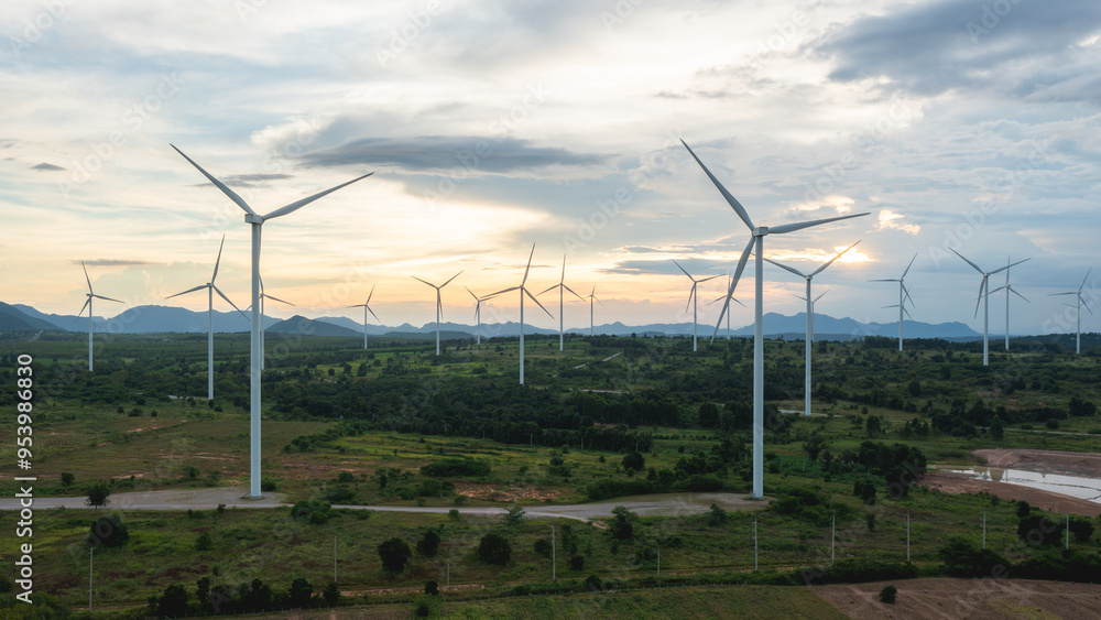 Obraz premium Wind turbines stand tall against a backdrop of cloudy skies, scattered across the expansive field. renewable energy.