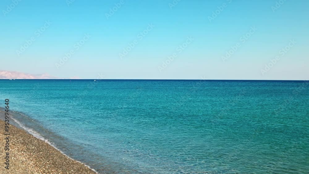 Stunning view of serene blue waters of Mediterranean Sea with gentle waves washing over pebble beach on Crete Island.