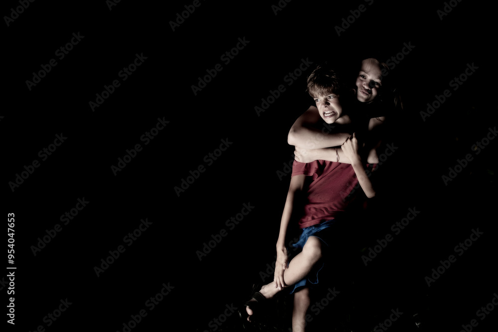 Portrait image of a brother and sister playing at night in the dark Portrait image of a brother and sister playing at night in the dark
