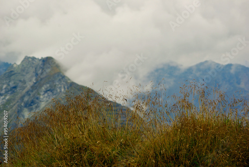 View of an amazing mountain landscape on a hazy day with gray clouds and fog over the peaks in autumn in Austria. photo