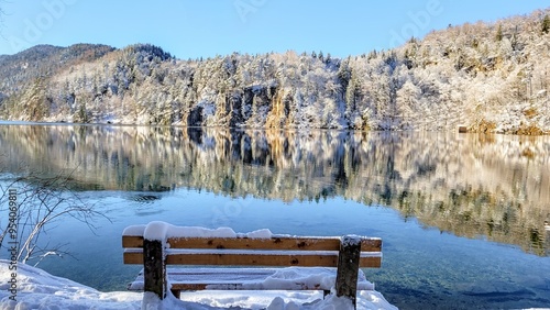 Bench overlooking a clear lake with reflections on a sunny winter day