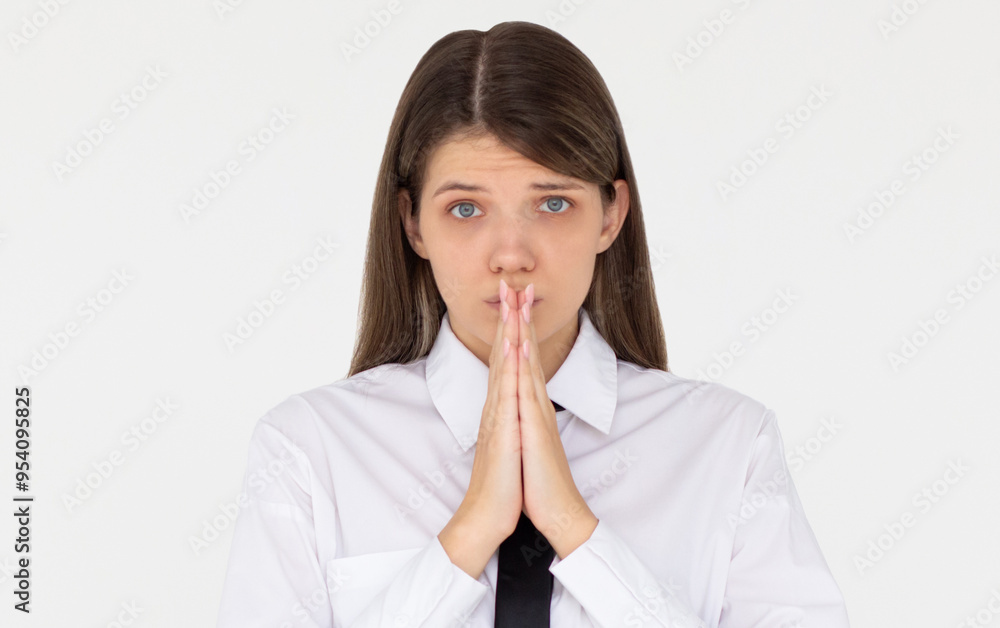 Portrait of imploring girl tilts head, purses lips, looks sadly at camera, makes praying gesture, asks for help and support, begs boyfriend for apologize, wears white shirt, isolated on white wall Portrait of imploring girl tilts head, purses lips, looks sadly at camera, makes praying gesture, asks for help and support, begs boyfriend for apologize, wears white shirt, isolated on white wall