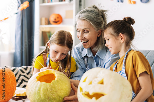 Fotografie Happy grandmother and granddaughters carving pumpkins together for halloween cel