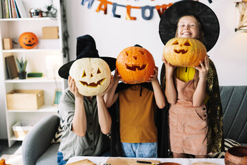 Senior woman and little, attractive girls costumes celebrating halloween posing with carved pumpkins
