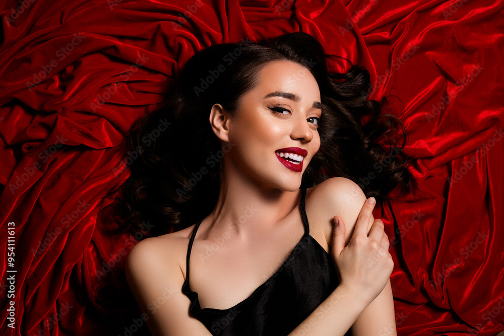 Top photo of gorgeous happy girl lying on red velvet textile background touch shoulder arm Top photo of gorgeous happy girl lying on red velvet textile background touch shoulder arm