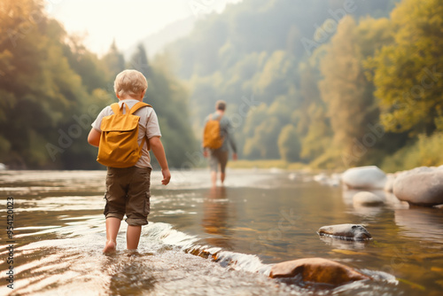 A child exploring a river while an adult strolls along the bank during a peaceful nature camping adventure