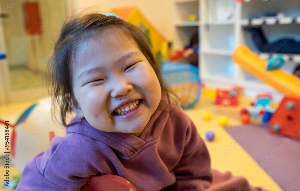 young girl is smiling and sitting on the floor in a room full of toys young girl is smiling and sitting on the floor in a room full of toys