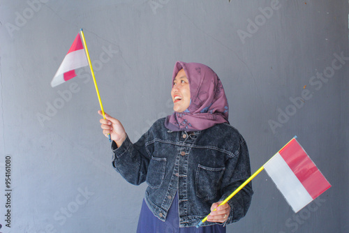 A woman in a purple hijab looks happy wearing a red and white cloth tie. The red and white flag is the national flag of Indonesia. photo