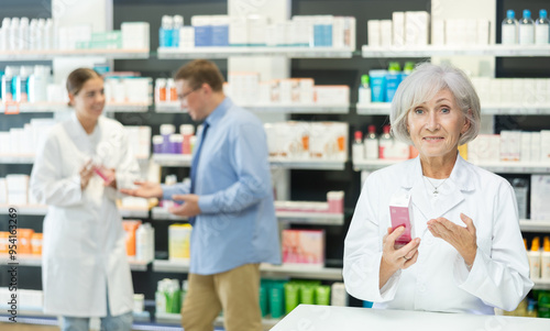 Portrait of elderly female pharmacist offering to buy medicine in a pharmacy