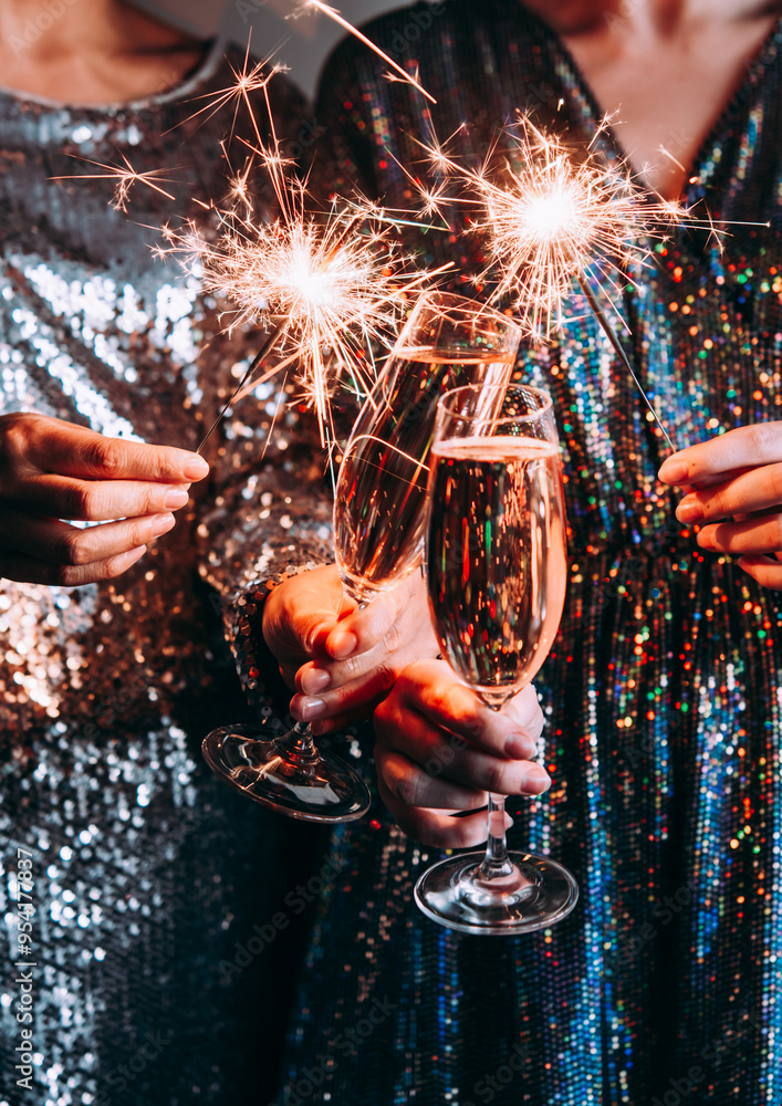 Friends celebrating Christmas or New Year eve party with Bengal lights and champagne.