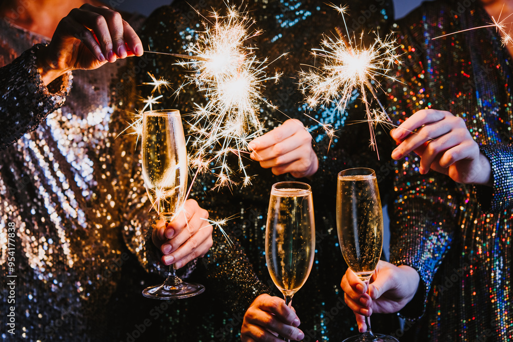 Friends celebrating Christmas or New Year eve party with Bengal lights and champagne.