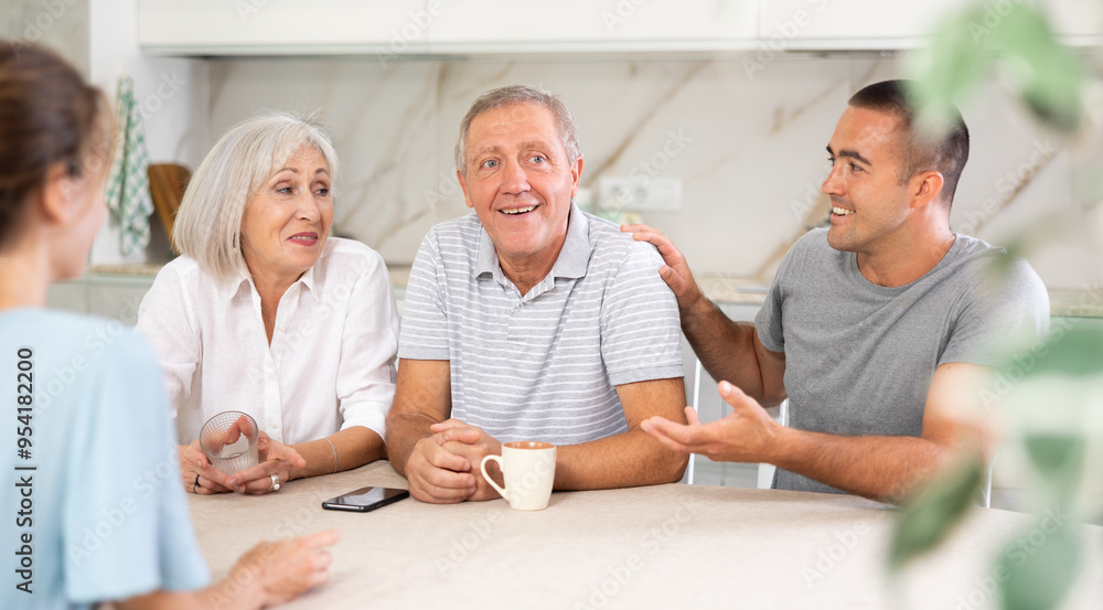 Obraz premium Family (mother, father, son, daughter) having fun talking in kitchen with each other