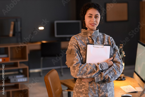 Female African-American soldier with headset and clipboard in headquarters at night