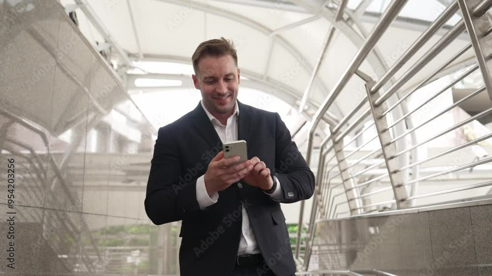 Smart businessman looking or checking his mobile phone while walking at corridor for going to workplace. Happy manager using telephone to send massage to marketing team and receive good news. Urbane. Smart businessman looking or checking his mobile phone while walking at corridor for going to workplace. Happy manager using telephone to send massage to marketing team and receive good news. Urbane.