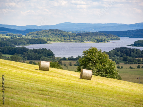 Round hay bales on a hillside with lake in valley europe photo