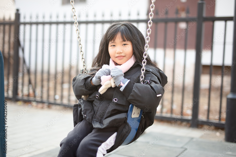 Cute little girl playing on a swing
