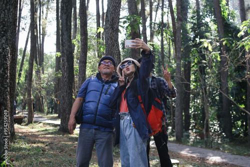 Asian Woman Taking Selfie Of Family Walking In Forest