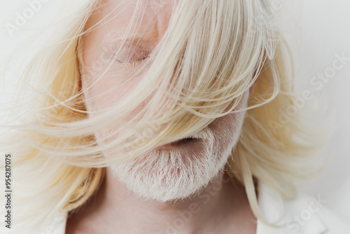 Man with long blonde hair and white beard, eyes closed, conveying serenity and peace, with soft light background emphasizing the subject s features and hair texture photo