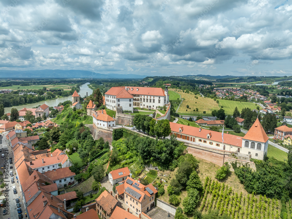Fototapeta premium Aerial view of Ptuj castle with red roof gothic renaissance palace building, bastions, towers on a hilltop above the old town, Drava river in Slovenia