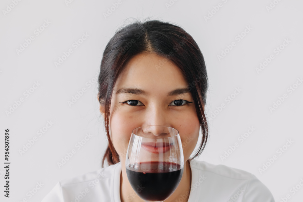 Asian Thai woman holding and showing a glass of red wine, happy smiling drinking while standing isolated over white background wall. Asian Thai woman holding and showing a glass of red wine, happy smiling drinking while standing isolated over white background wall.