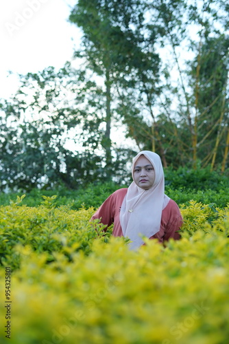 A Muslim woman is enjoying flowers in the garden