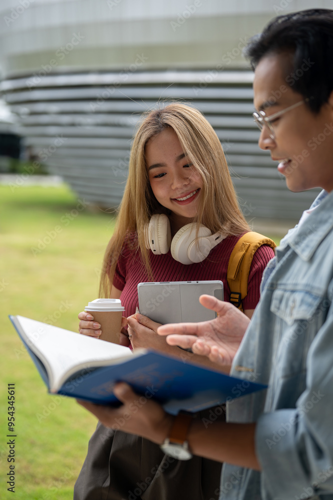 Two happy and cheerful young Asian college students are looking at a book and discussing homework. Two happy and cheerful young Asian college students are looking at a book and discussing homework.