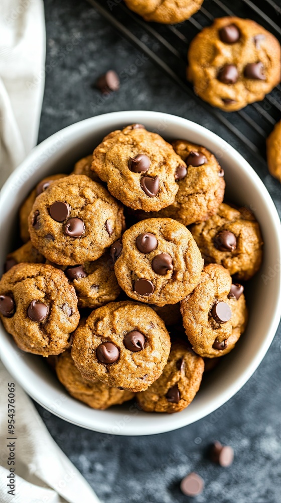 A white bowl filled with chocolate chip cookies, close-up. A white bowl filled with chocolate chip cookies, close-up.