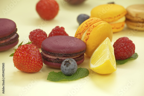 Group of colorful macaroons and fruits over yellow