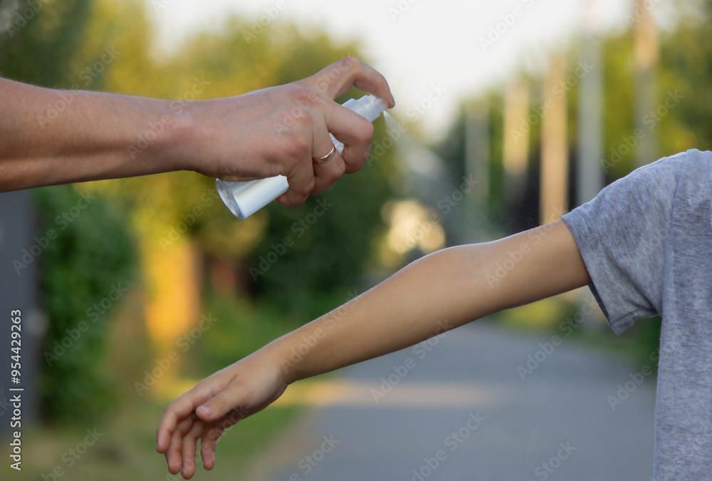 woman applies insect repellent to her son's hand in the park, close-up. Prevention of bites woman applies insect repellent to her son's hand in the park, close-up. Prevention of bites
