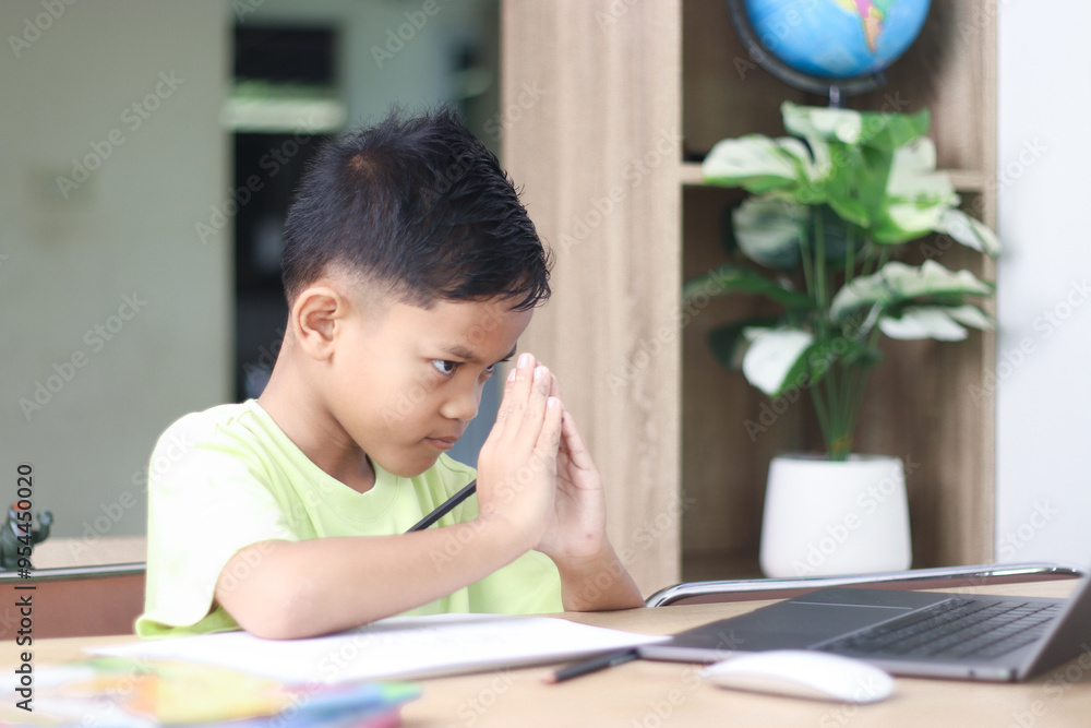 A Happy little asian boy studying online learning class with online video call zoom teacher at home. E-learning or Home schooling education concept. A Happy little asian boy studying online learning class with online video call zoom teacher at home. E-learning or Home schooling education concept.