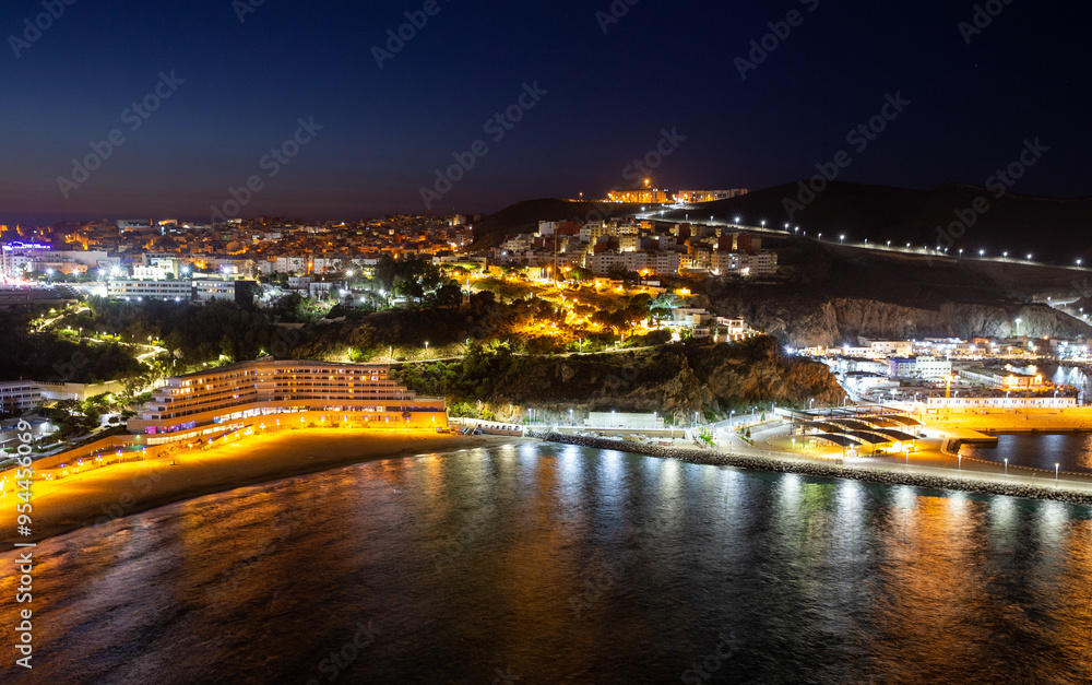 Fototapeta premium Picturesque night view of Al Hoceima city and modern hotel buildings on the shore of the Mediterranean Sea bay