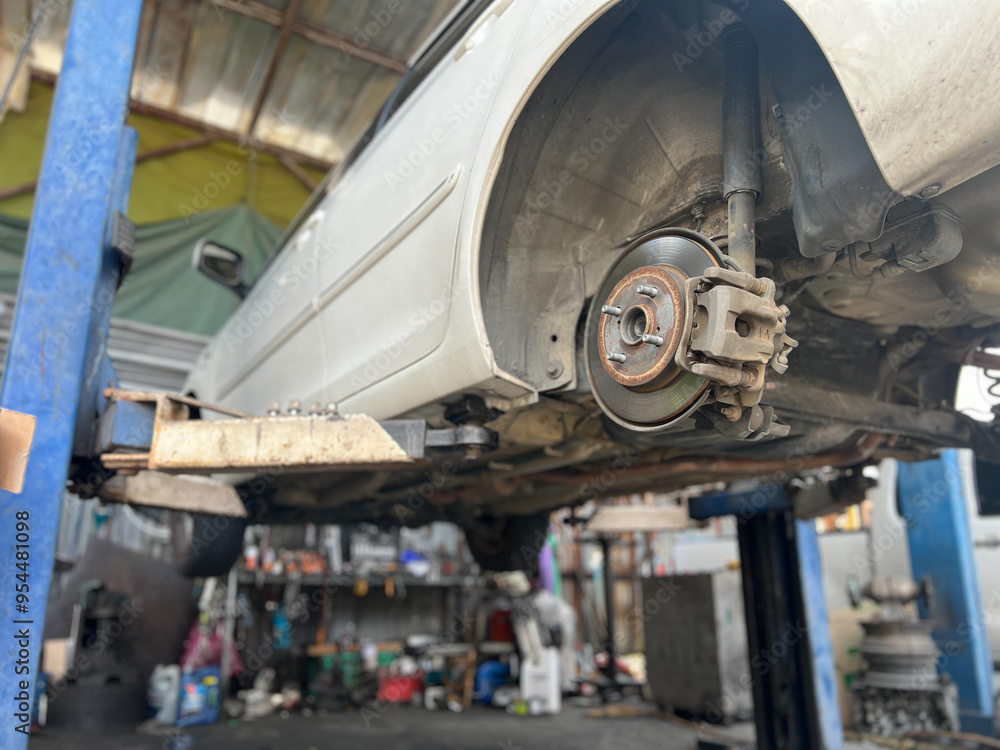 custom made wallpaper toronto digitalA car being serviced on lift in garage, showcasing undercarriage and brake components.