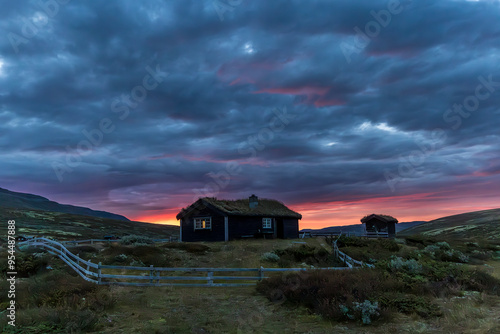 Sunrise over a typical wooden house under a cloudy sky, Dovrefjell region, Norway