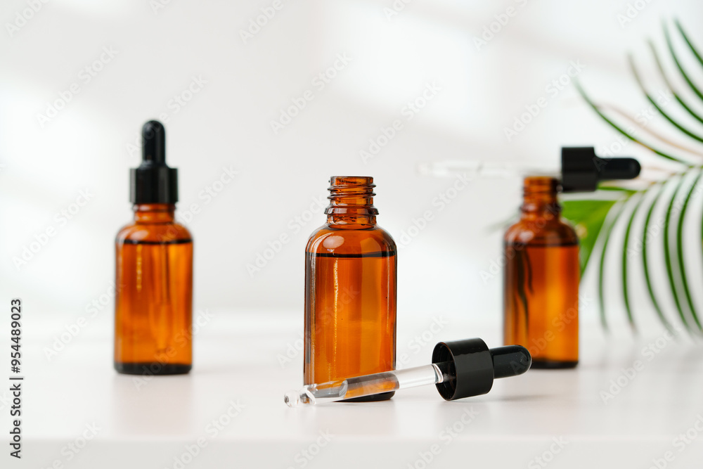 Collection of Amber Glass Bottles and Jars for Essential Oils on a White Surface Collection of Amber Glass Bottles and Jars for Essential Oils on a White Surface